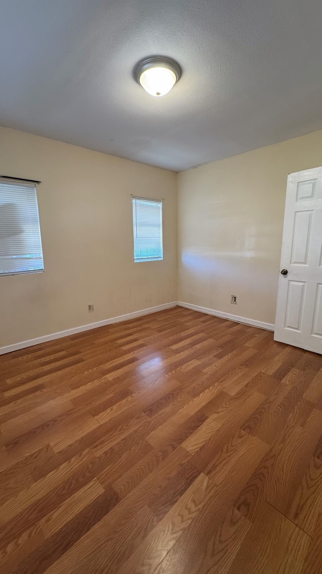 empty room with hardwood / wood-style floors and a textured ceiling