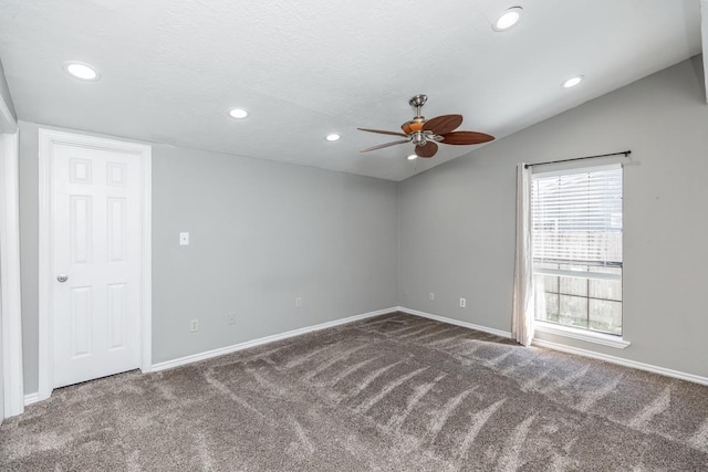 carpeted spare room featuring a textured ceiling, ceiling fan, and vaulted ceiling