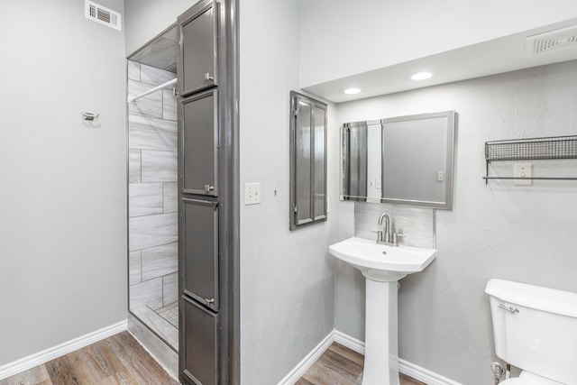 bathroom with tasteful backsplash, sink, a shower, wood-type flooring, and toilet