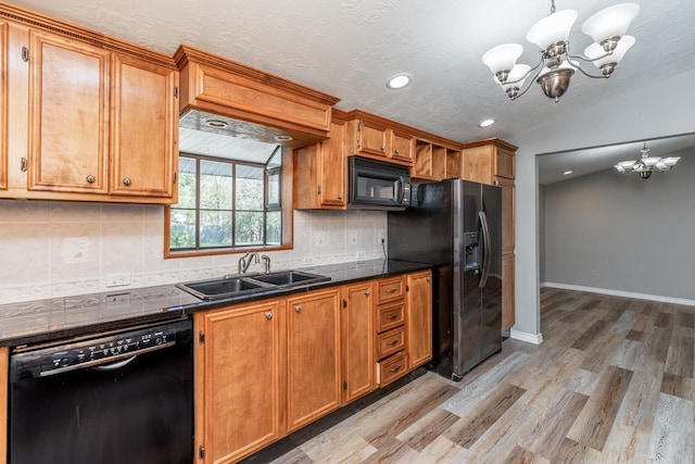 kitchen featuring sink, hanging light fixtures, a chandelier, lofted ceiling, and black appliances