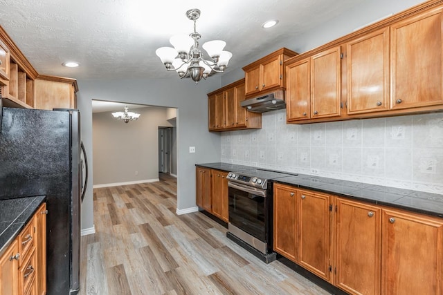 kitchen with hanging light fixtures, a chandelier, stainless steel range with electric stovetop, and black refrigerator