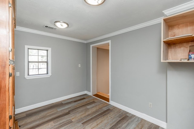 unfurnished room with hardwood / wood-style floors and crown molding