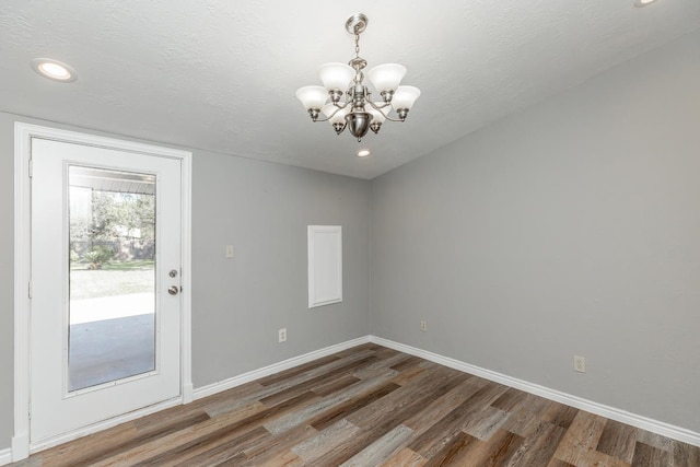 unfurnished room with a textured ceiling, dark hardwood / wood-style floors, and a notable chandelier