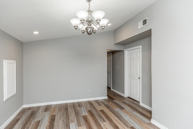 empty room featuring hardwood / wood-style floors and a chandelier