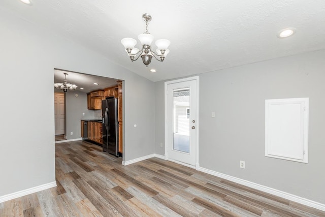 interior space with a notable chandelier, wood-type flooring, a textured ceiling, and vaulted ceiling