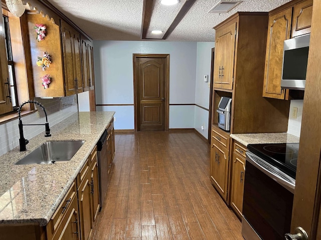 kitchen featuring stainless steel appliances, sink, light stone counters, tasteful backsplash, and dark hardwood / wood-style floors