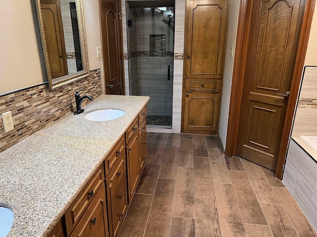 bathroom featuring a shower with door, tasteful backsplash, and vanity