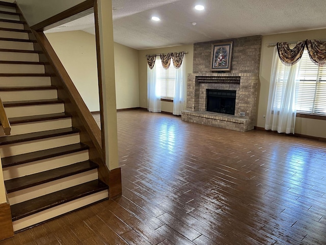 unfurnished living room with a fireplace, a textured ceiling, and dark wood-type flooring