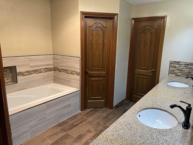 bathroom featuring tiled bath and vanity