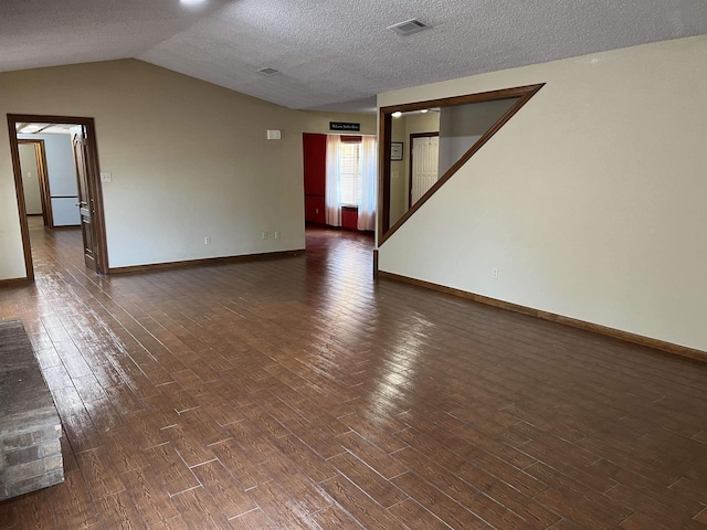 empty room with dark hardwood / wood-style flooring, a textured ceiling, and vaulted ceiling