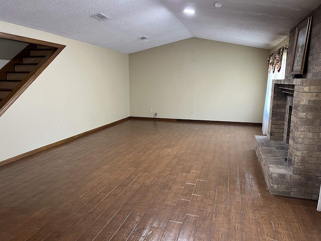 unfurnished living room featuring lofted ceiling, a fireplace, a textured ceiling, and dark wood-type flooring