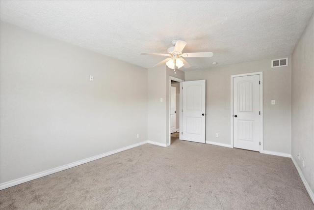 unfurnished bedroom with ceiling fan, light colored carpet, and a textured ceiling