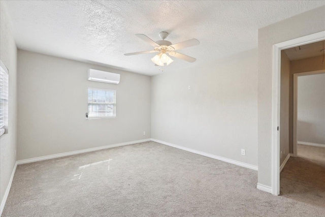 spare room featuring light colored carpet, a wall unit AC, ceiling fan, and a textured ceiling