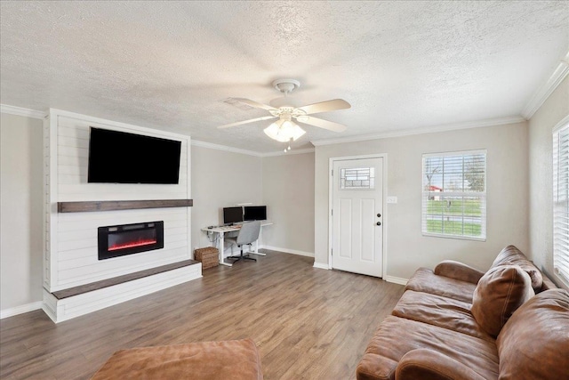 living room with a textured ceiling, a large fireplace, ornamental molding, ceiling fan, and hardwood / wood-style floors