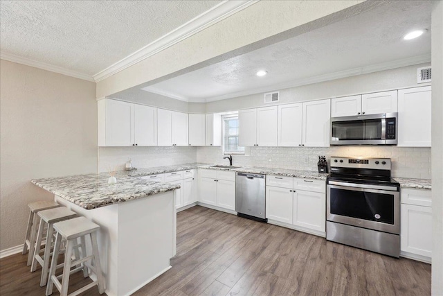 kitchen featuring stainless steel appliances, white cabinetry, a kitchen breakfast bar, and kitchen peninsula