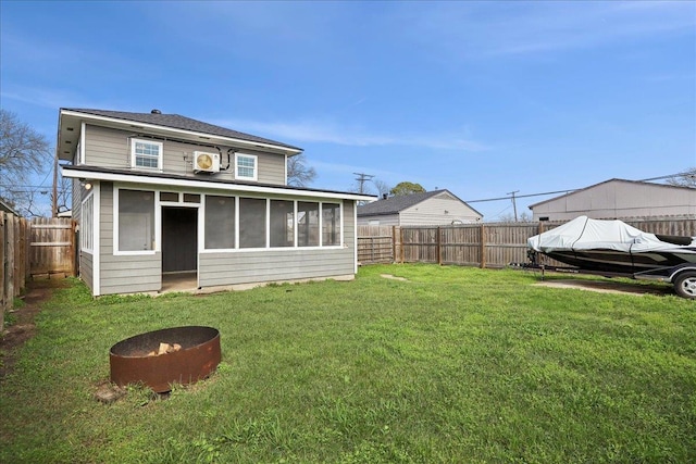 rear view of house featuring a lawn, a sunroom, and an outdoor fire pit