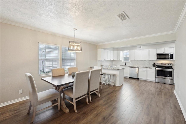 dining space featuring sink, crown molding, a textured ceiling, dark hardwood / wood-style flooring, and a chandelier