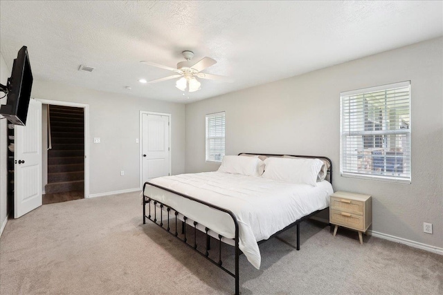 bedroom with light carpet, ceiling fan, and a textured ceiling