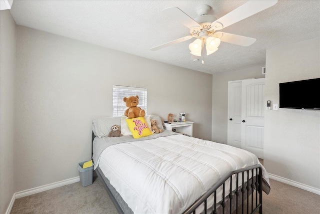 bedroom featuring ceiling fan, light colored carpet, a closet, and a textured ceiling