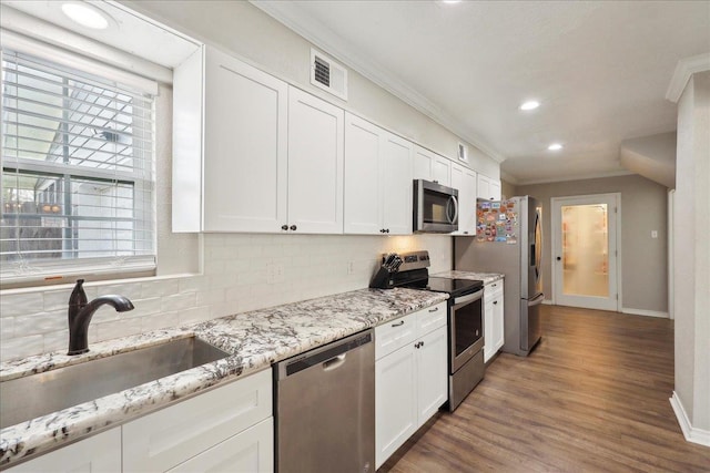 kitchen with sink, backsplash, white cabinets, and appliances with stainless steel finishes