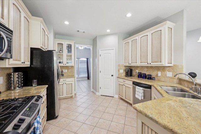7820 N Windemere Dr, Beaumont, TX 77713 - kitchen with stainless steel appliances, a sink, backsplash, light tile patterned flooring, and glass insert cabinets