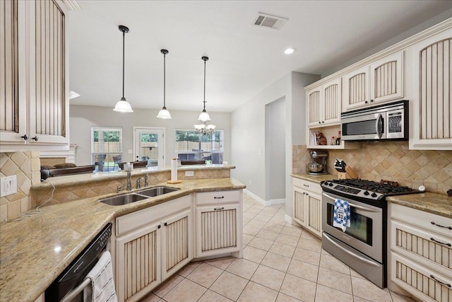 7820 N Windemere Dr, Beaumont, TX 77713 - kitchen featuring stainless steel appliances, a sink, cream cabinetry, a chandelier, and tasteful backsplash