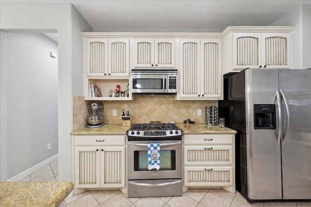 7820 N Windemere Dr, Beaumont, TX 77713 - kitchen with appliances with stainless steel finishes, cream cabinetry, tasteful backsplash, and light tile patterned flooring