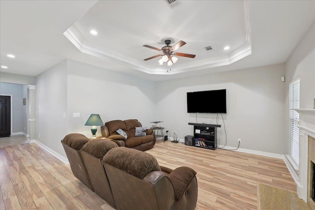 7820 N Windemere Dr, Beaumont, TX 77713 - living room featuring light wood finished floors, ceiling fan, a fireplace, a tray ceiling, and crown molding
