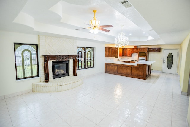 living room with a fireplace, ceiling fan, light tile patterned floors, and a tray ceiling