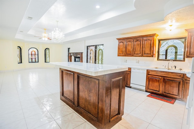 kitchen featuring a kitchen island, sink, a raised ceiling, white dishwasher, and light tile patterned floors