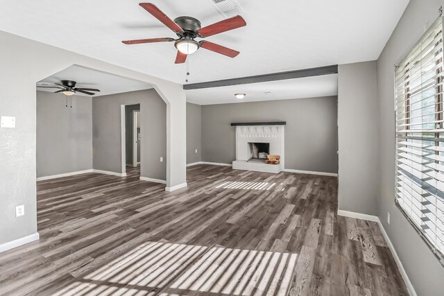 unfurnished living room with ceiling fan, dark hardwood / wood-style flooring, and a brick fireplace