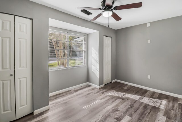 interior space with multiple closets, ceiling fan, and hardwood / wood-style floors