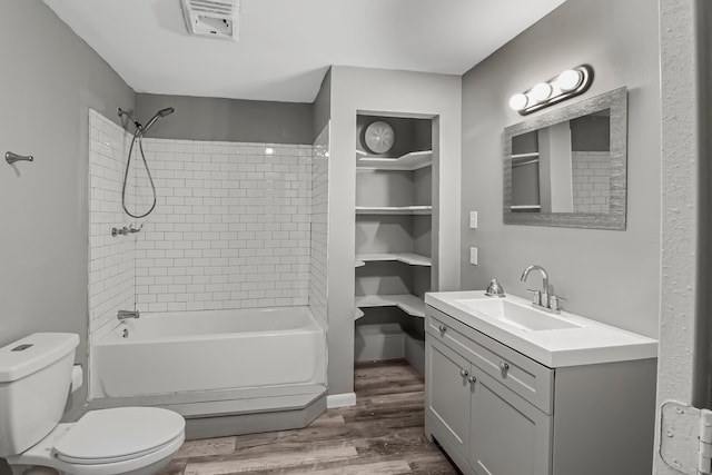 full bathroom with hardwood / wood-style floors, vanity, toilet, and tiled shower / bath