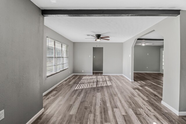 unfurnished living room featuring ceiling fan, hardwood / wood-style floors, and beamed ceiling