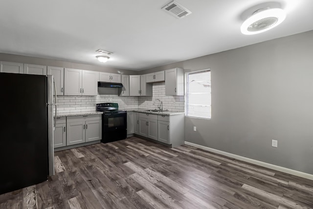 kitchen with gray cabinetry, stainless steel fridge, black electric range oven, and light stone countertops