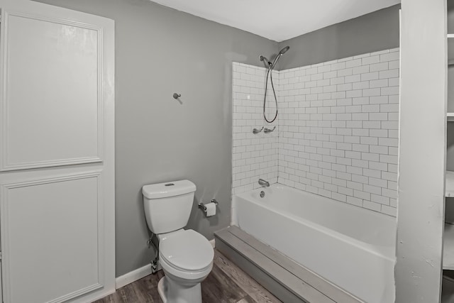 bathroom featuring hardwood / wood-style floors, tiled shower / bath combo, and toilet