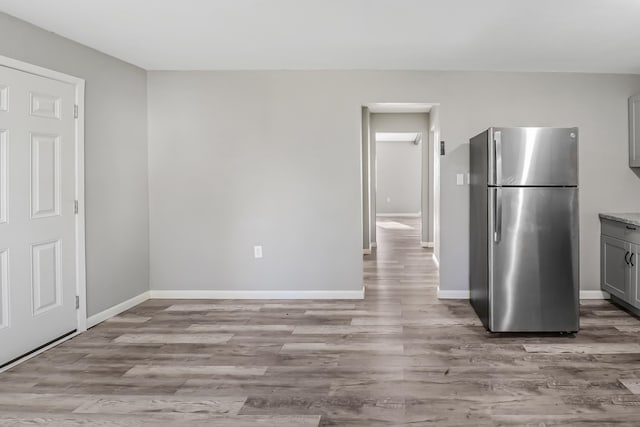 kitchen with stainless steel refrigerator, gray cabinets, and light wood-type flooring