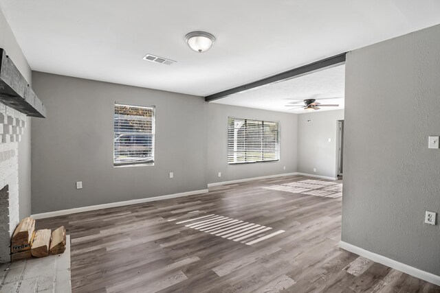 unfurnished living room with hardwood / wood-style floors, ceiling fan, a wealth of natural light, and a brick fireplace