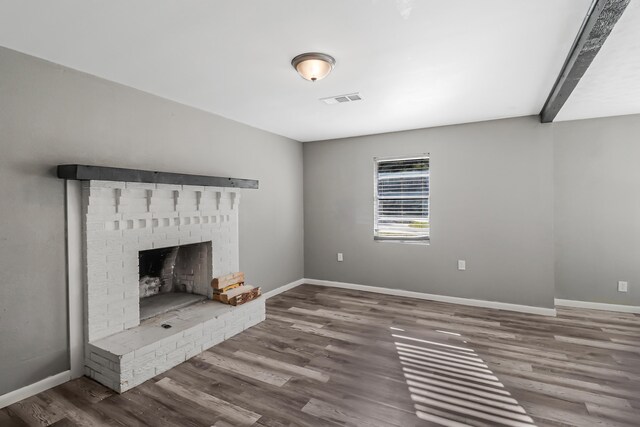 unfurnished living room featuring hardwood / wood-style flooring and a brick fireplace