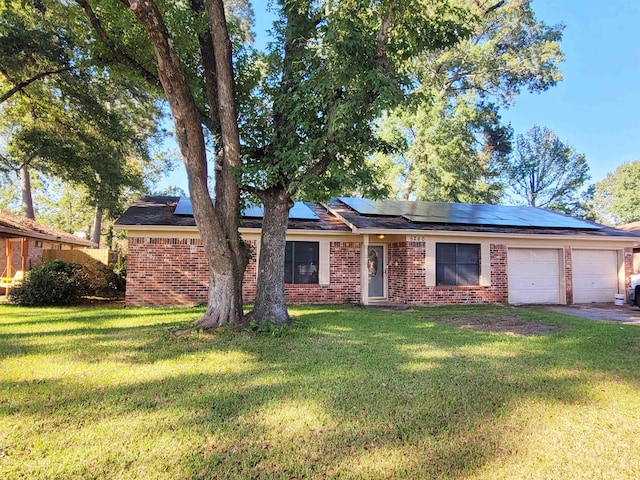 ranch-style house featuring a garage, a front lawn, and solar panels