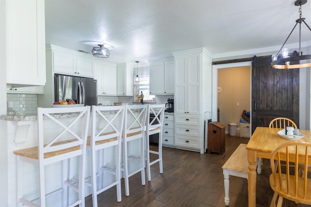 310 Medford Ln, Vidor, TX 77662 - kitchen with white cabinetry, a barn door, a breakfast bar, and stainless steel refrigerator with ice dispenser