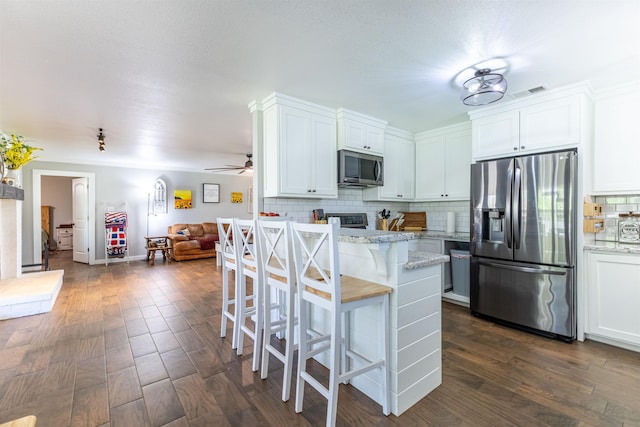 310 Medford Ln, Vidor, TX 77662 - kitchen featuring a breakfast bar area, decorative backsplash, visible vents, white cabinets, and appliances with stainless steel finishes