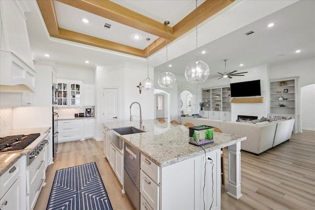 14990 Michelle Ln, Beaumont, TX 77713 - kitchen with a sink, appliances with stainless steel finishes, a ceiling fan, a large fireplace, and white cabinetry