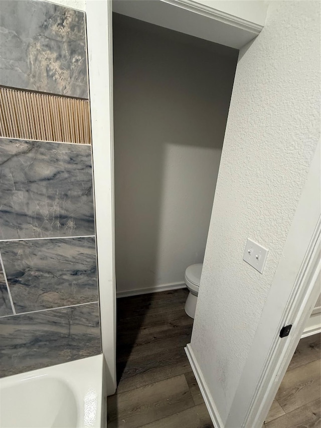 bathroom with a bathtub, wood-type flooring, and toilet