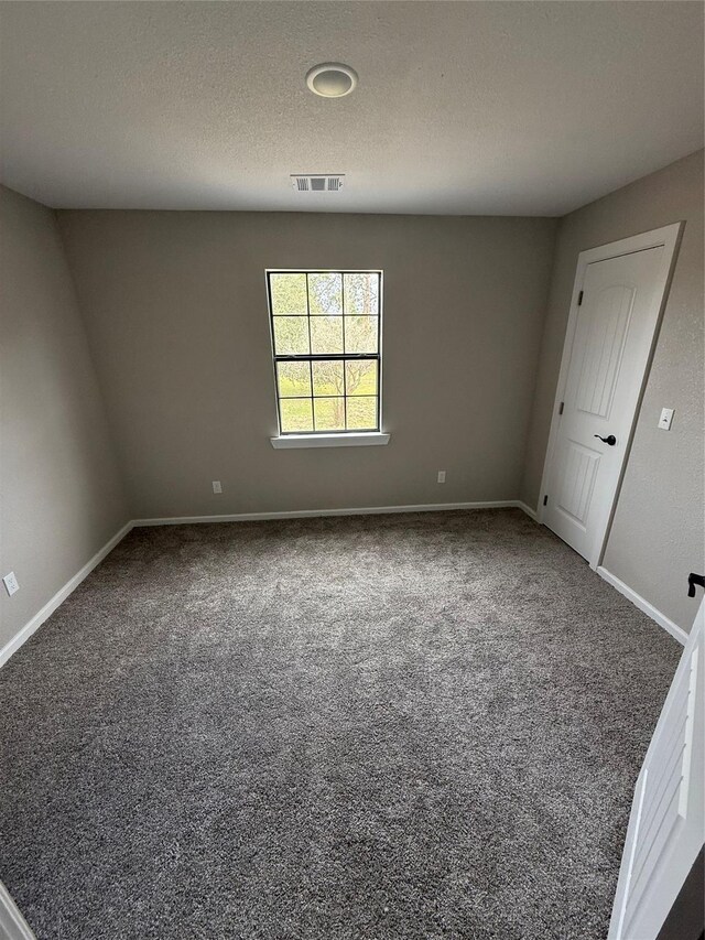 carpeted empty room featuring a textured ceiling