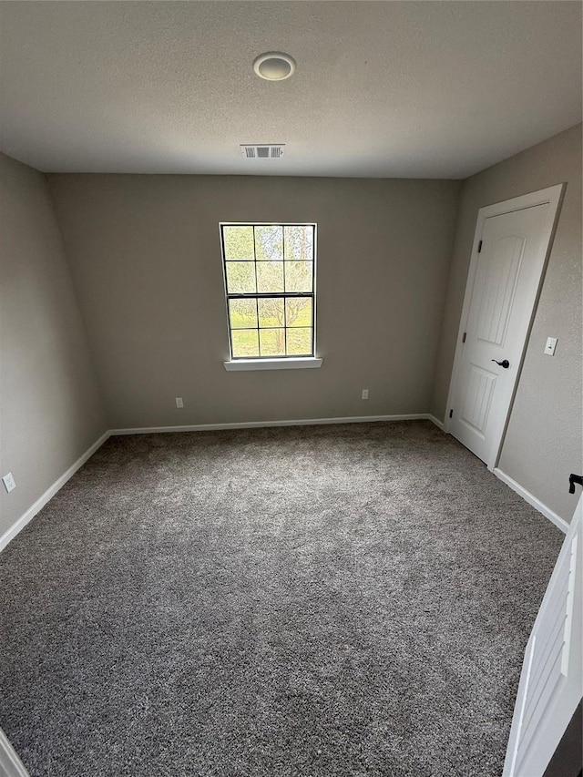 carpeted empty room featuring a textured ceiling