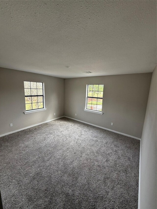 carpeted empty room featuring a textured ceiling