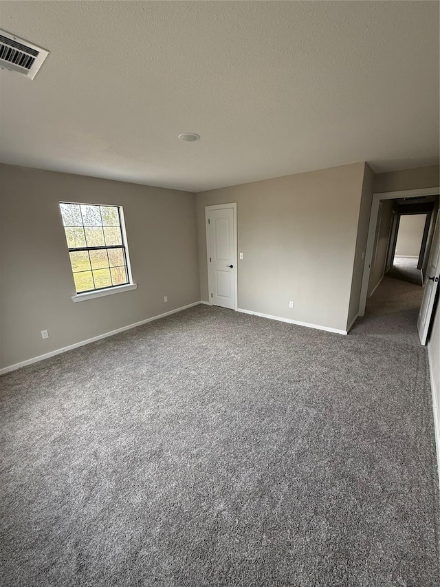 empty room featuring a textured ceiling and dark carpet