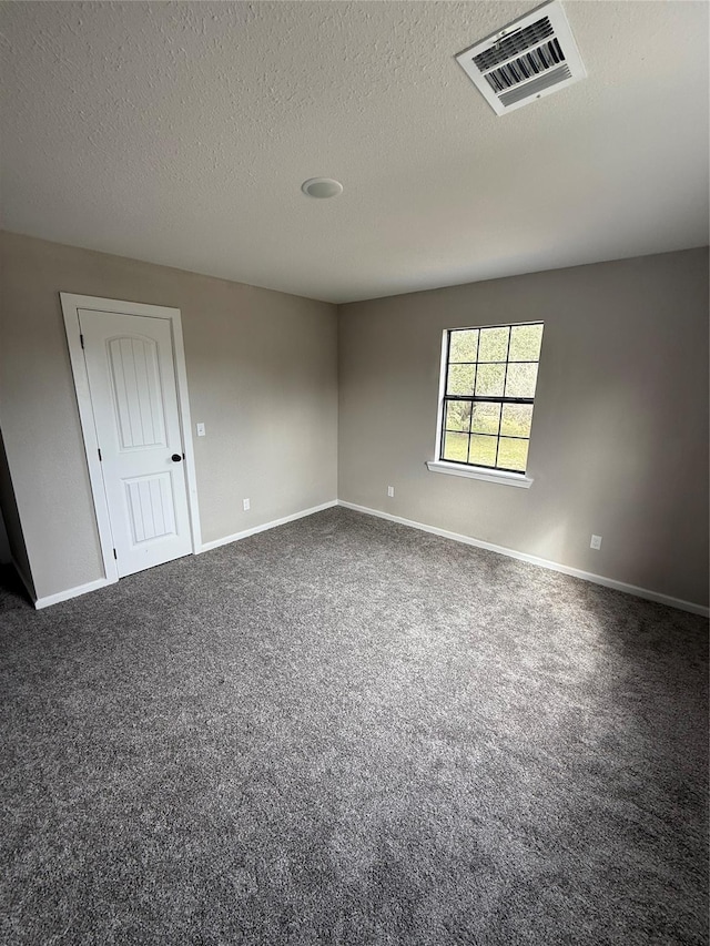 carpeted empty room featuring a textured ceiling