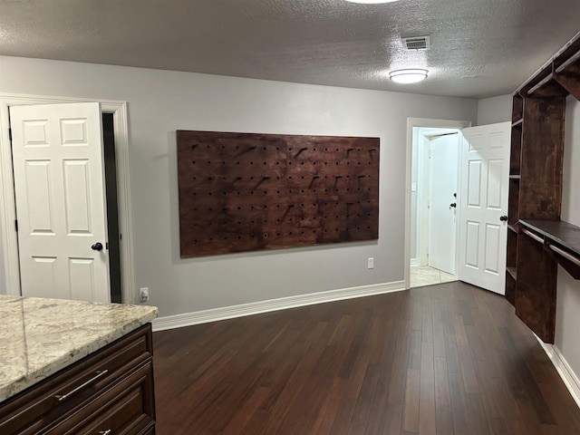 unfurnished dining area with a textured ceiling and dark wood-type flooring